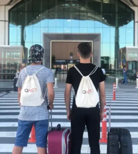 2 boys standing at a crosswalk with qnet logo on backpack for qnet manchester city